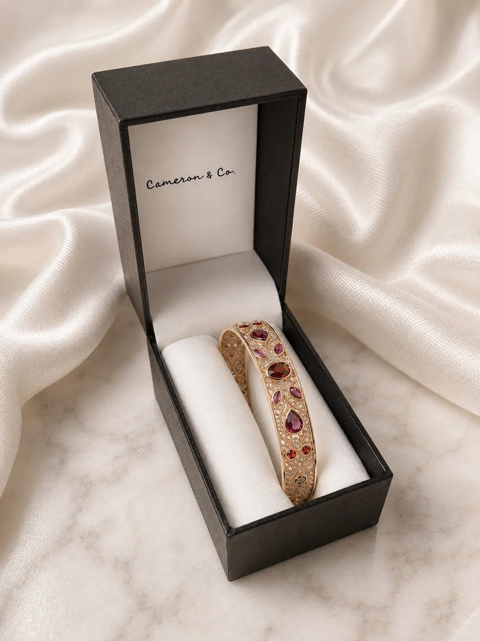 Gold gemstone bangle stored securely in a Cameron & Co jewellery box on white satin and marble